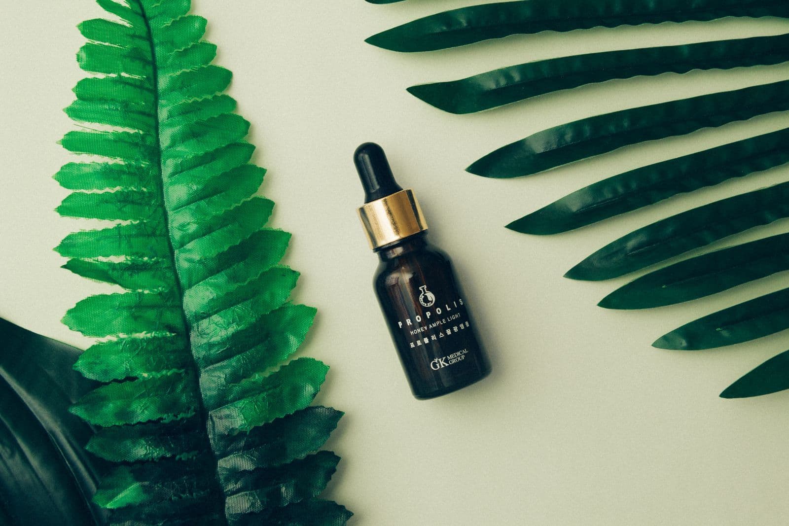 Chai serum dưỡng ẩm bên cạnh lá xanh phù hợp chăm sóc da mùa khô