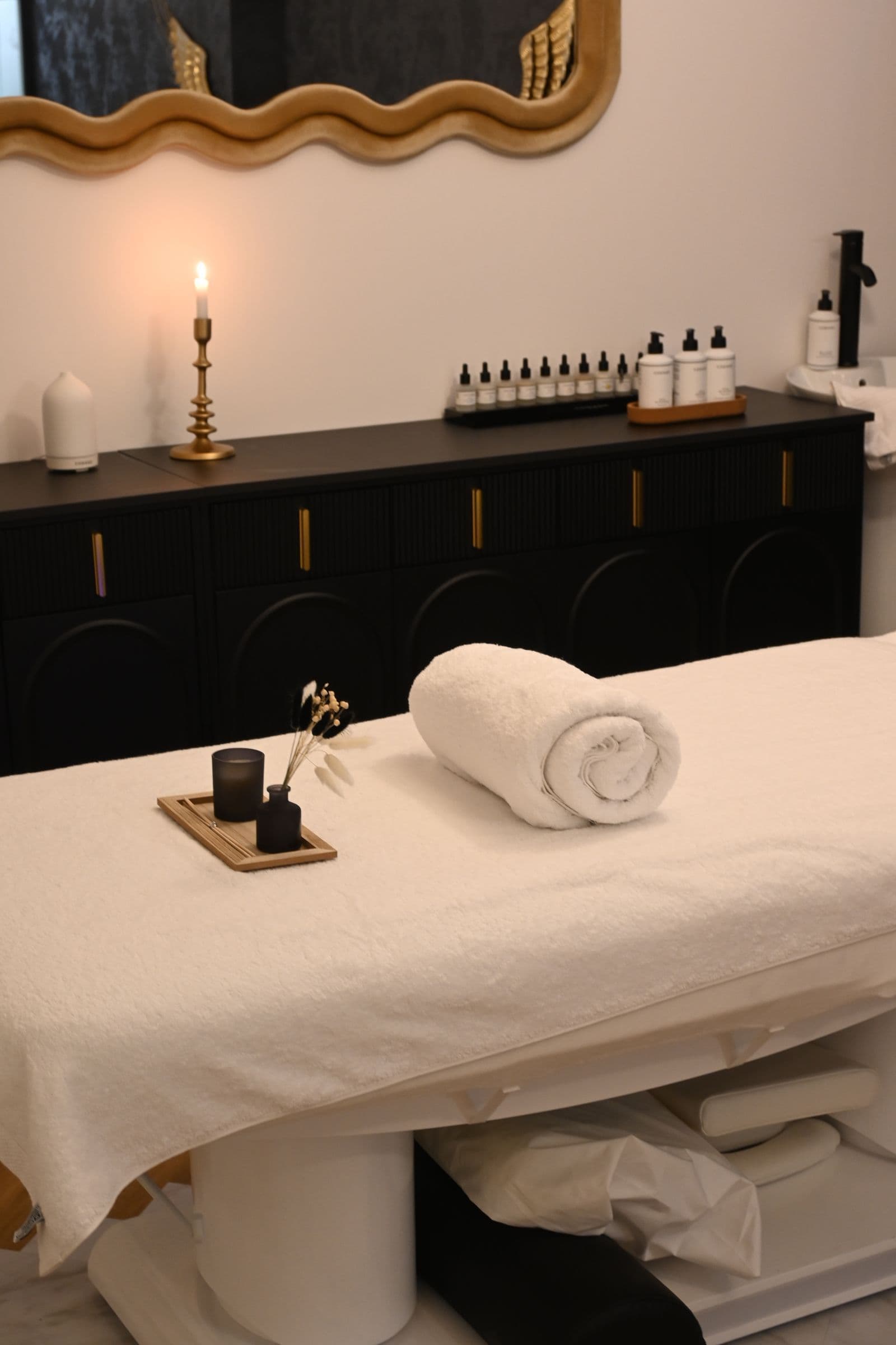 Không gian spa yên tĩnh với giường massage, khăn và nến thư giãn