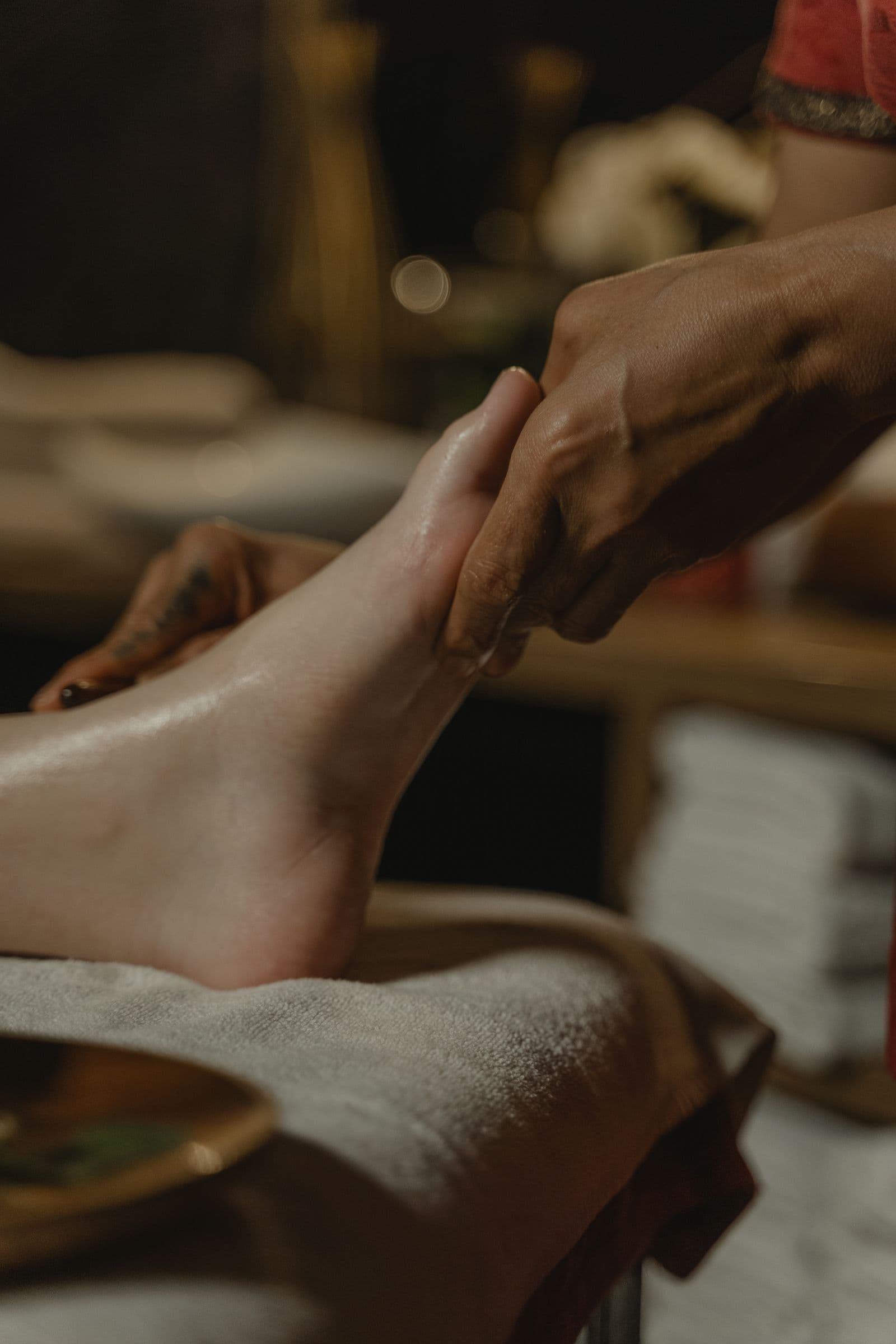 Thao tác massage chân cận cảnh trong không gian spa yên tĩnh buổi tối